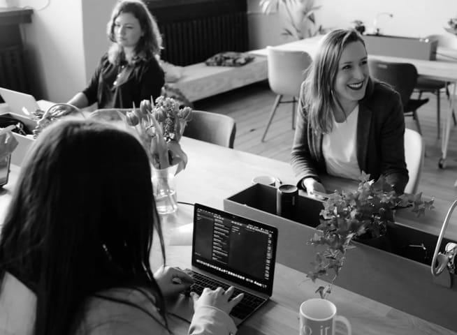 Three women working on computers in an office.